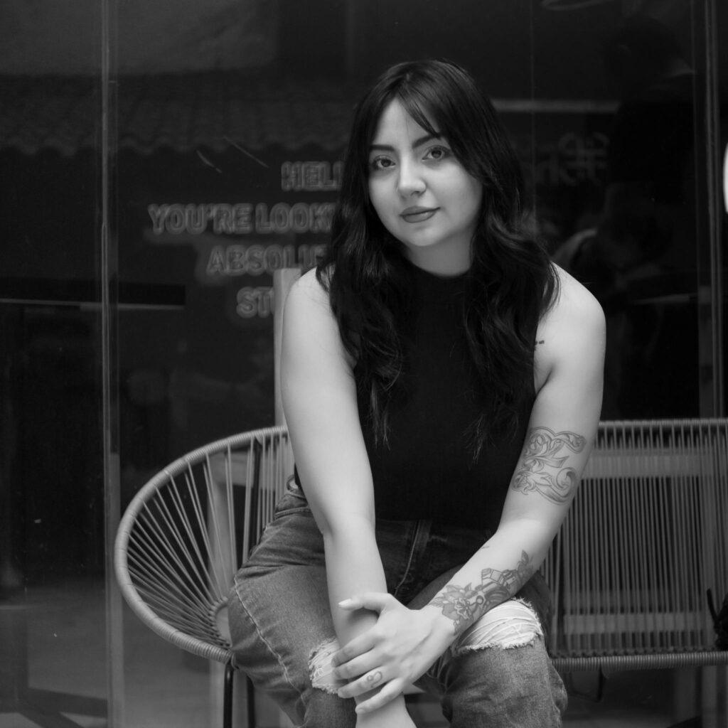 Elegant black and white portrait of a tattooed woman sitting indoors in Mexico City.