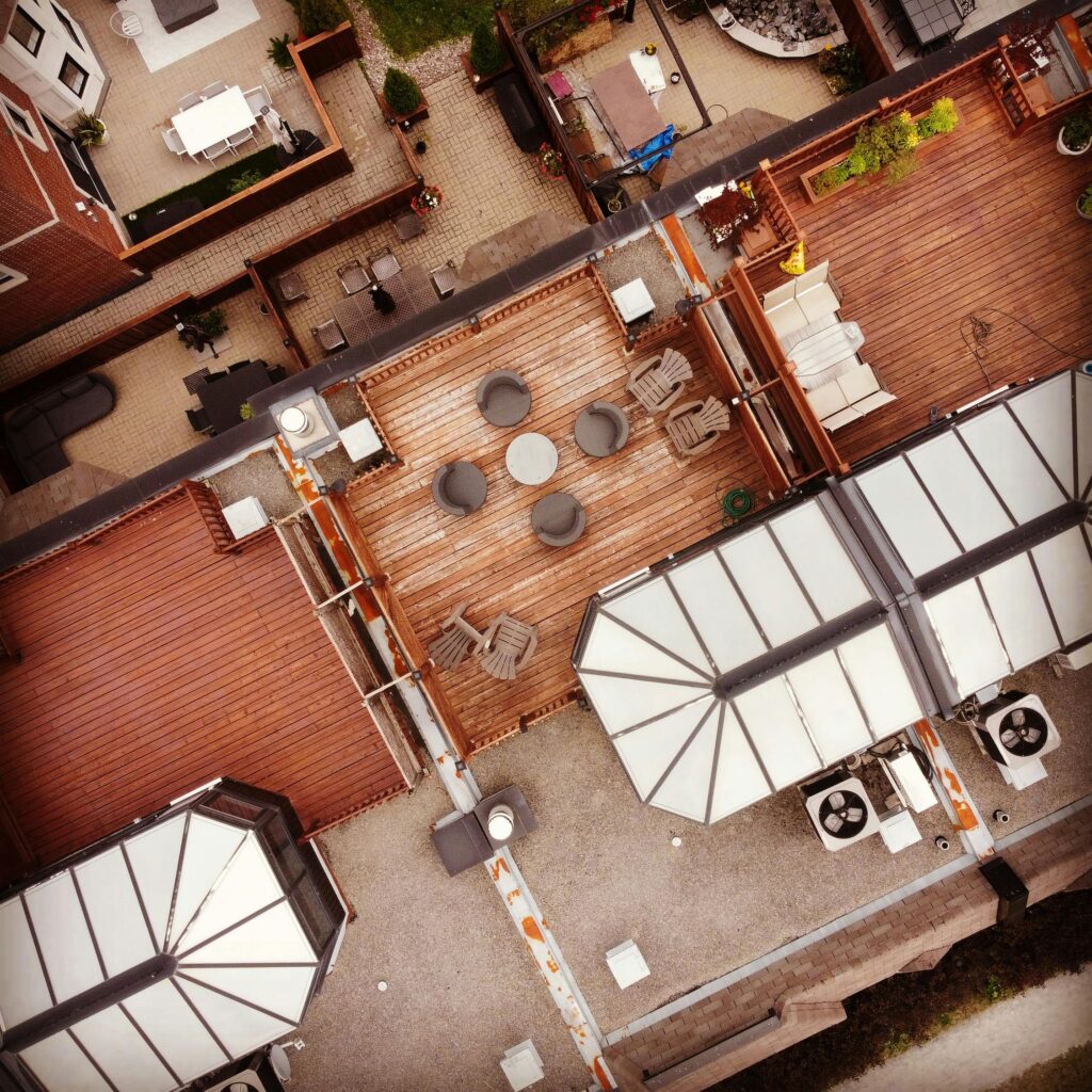 Drone shot capturing contemporary rooftop patio with seating arrangements and greenery.